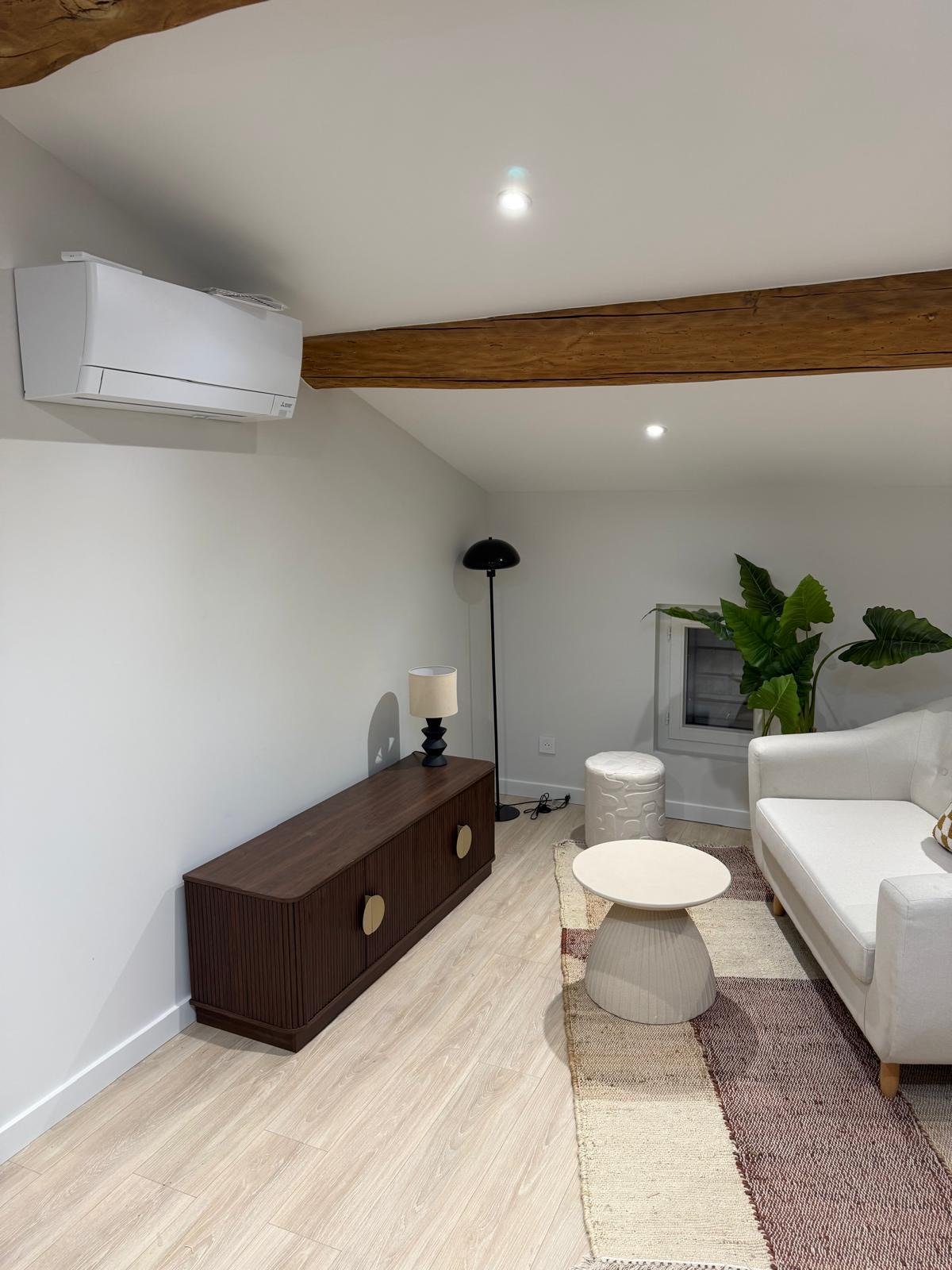 Salon avec climatisation, meuble en bois et canapé blanc