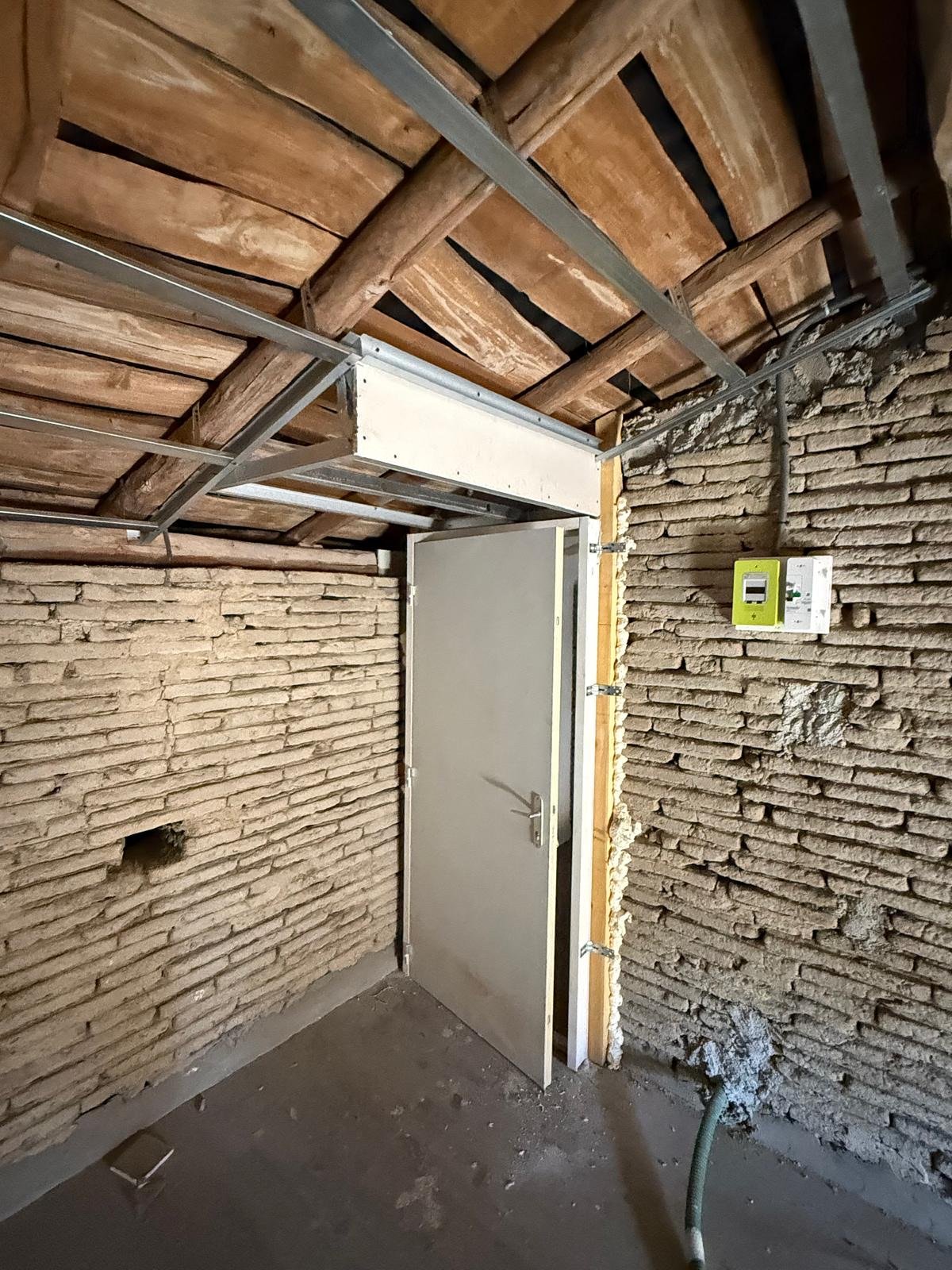 Comble à l'état brut, murs en brique et charpente bois apparente